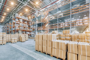 large industrial warehouse with high racks. In the foreground are a lot of cardboard boxes. Overloaded warehouse building